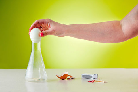 science experiment called egg in a bottle being demonstrated by an adult