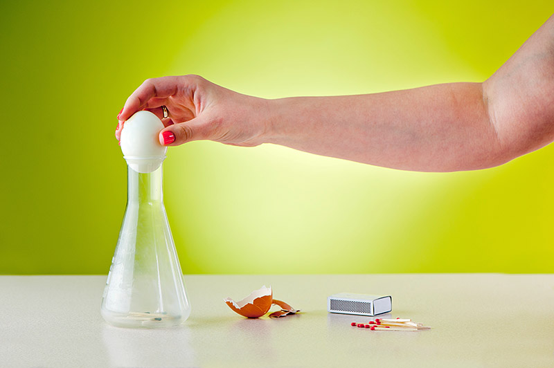 science experiment called egg in a bottle being demonstrated by an adult