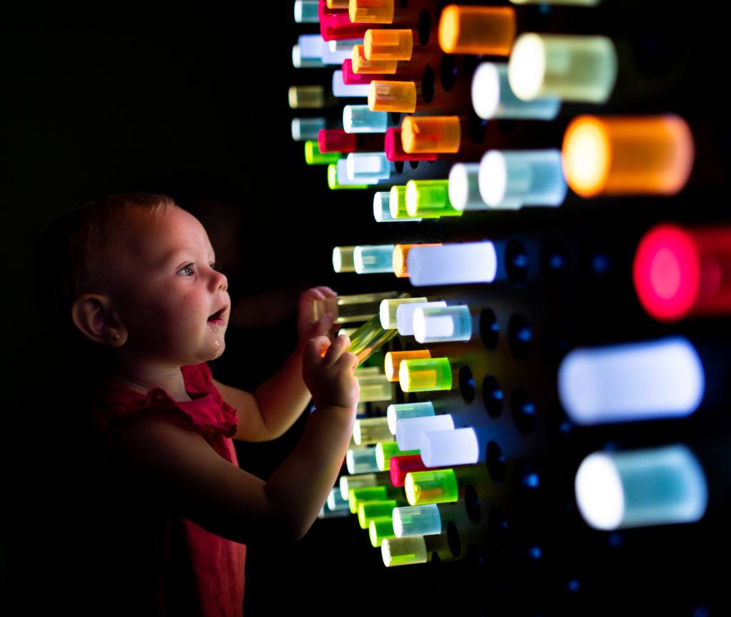 infant playing with light-up wall