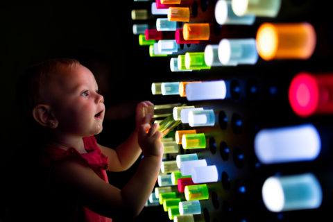 infant playing with light-up wall