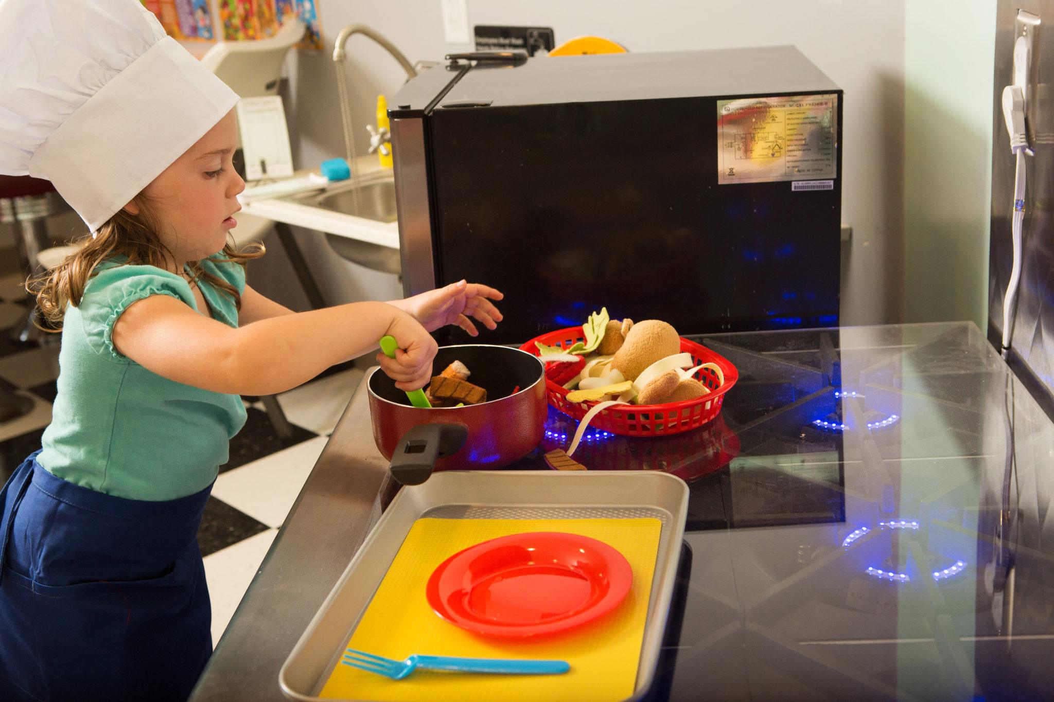 Niño jugando con un horno de juguete