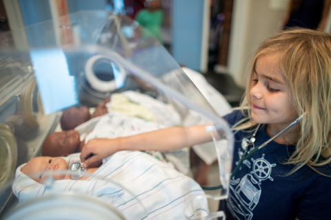 child tending to baby doll in medical lab playroom
