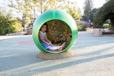 Child sitting inside green butterfly ball statue