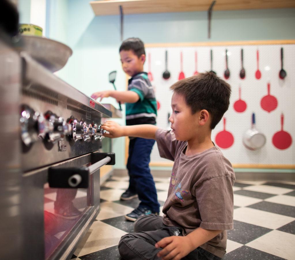 children playing with oven in pretend kitchen