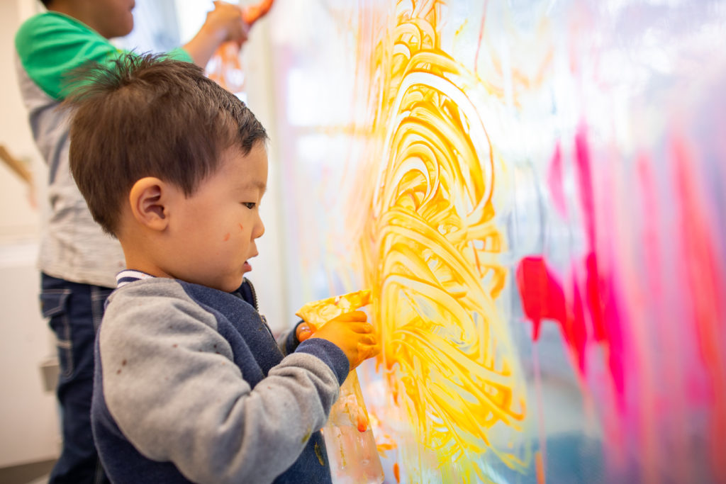 child painting with fingers on window