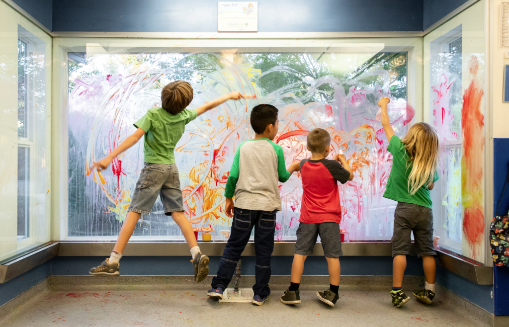 several kids playing at paint window
