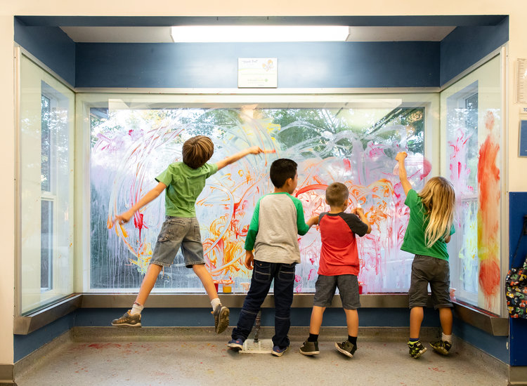 Niños pintando con los dedos en la ventana