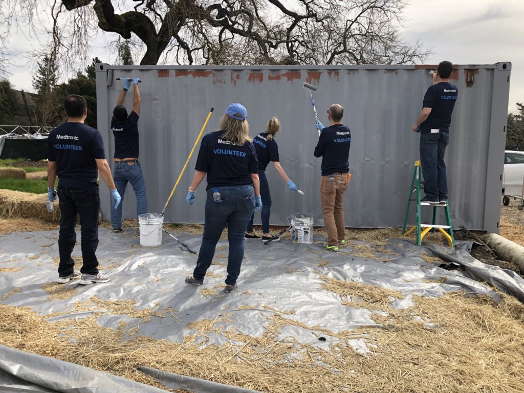 voluntarios pintando un contenedor de carga