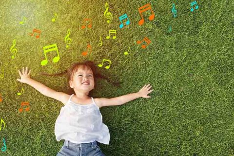 little girl smile and lay on grass with music note background