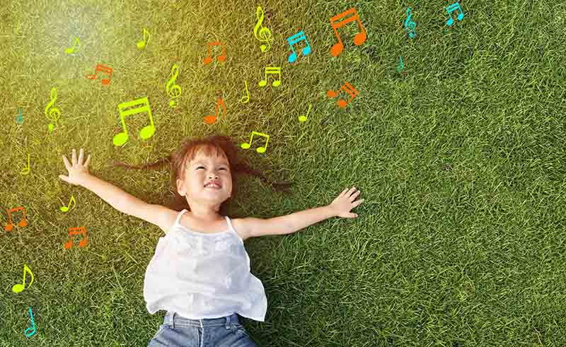 little girl smile and lay on grass with music note background