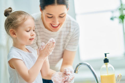 A cute little girl and her mother are washing their hands. Protection against infections and viruses.