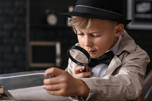 Cute little detective working with evidence at table