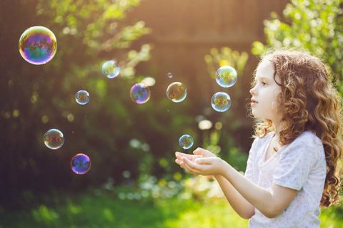 little girl catching bubbles in the backyard