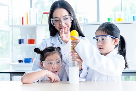 madre y dos niños haciendo un experimento científico de inflado de globos en casa