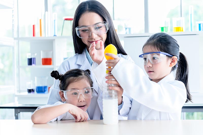 madre y dos niños haciendo un experimento científico de inflado de globos en casa