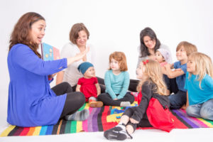 children gathered around a teach reading a book in Spanish