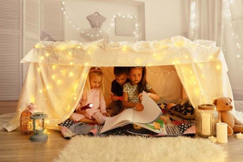 children playing in a blanket fort in their living room