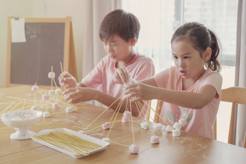 dos niños usando malvaviscos y pinchos en un experimento científico