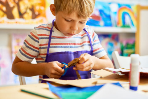 un niño usando las tijeras para un proyecto de artesanía de papel