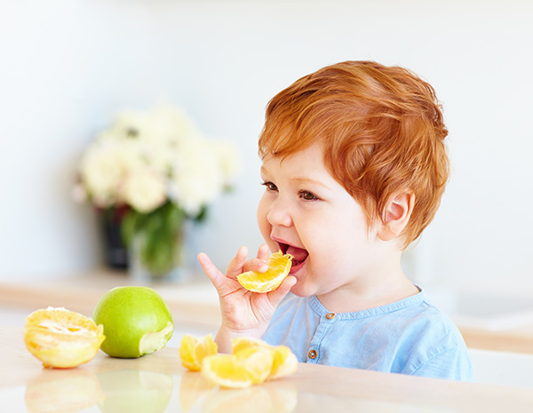 young redheaded child taste testing sour fruits for sensory activity play