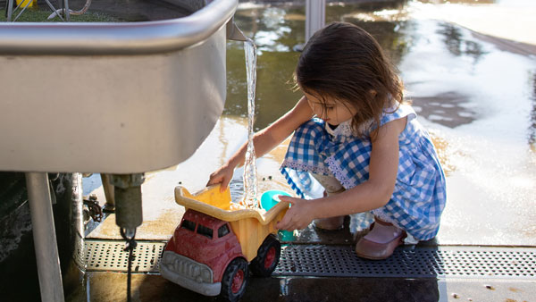 young girl playing with water stream at the childrens museum