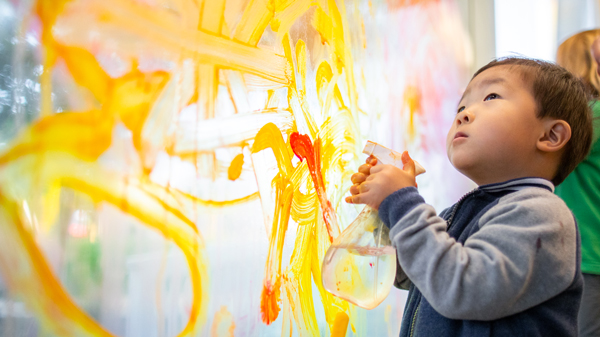 Un niño pequeño jugando con una botella de spray en el muro de arte interactivo del Museo de los Niños del Condado de Sonoma