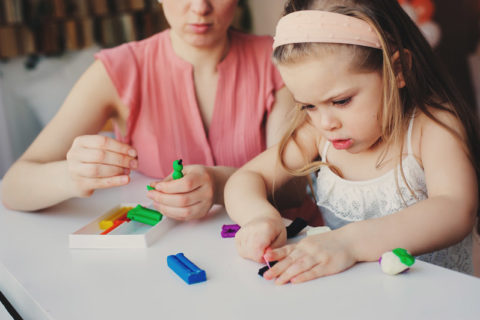 woman observing her child play with playdough