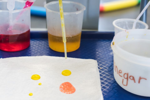pipeta goteando agua coloreada sobre un paño en un experimento infantil