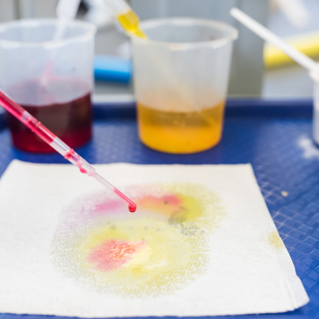 pipeta goteando agua coloreada sobre un paño en un experimento infantil