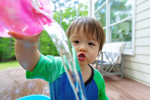 Young toddler boy playing with water outside