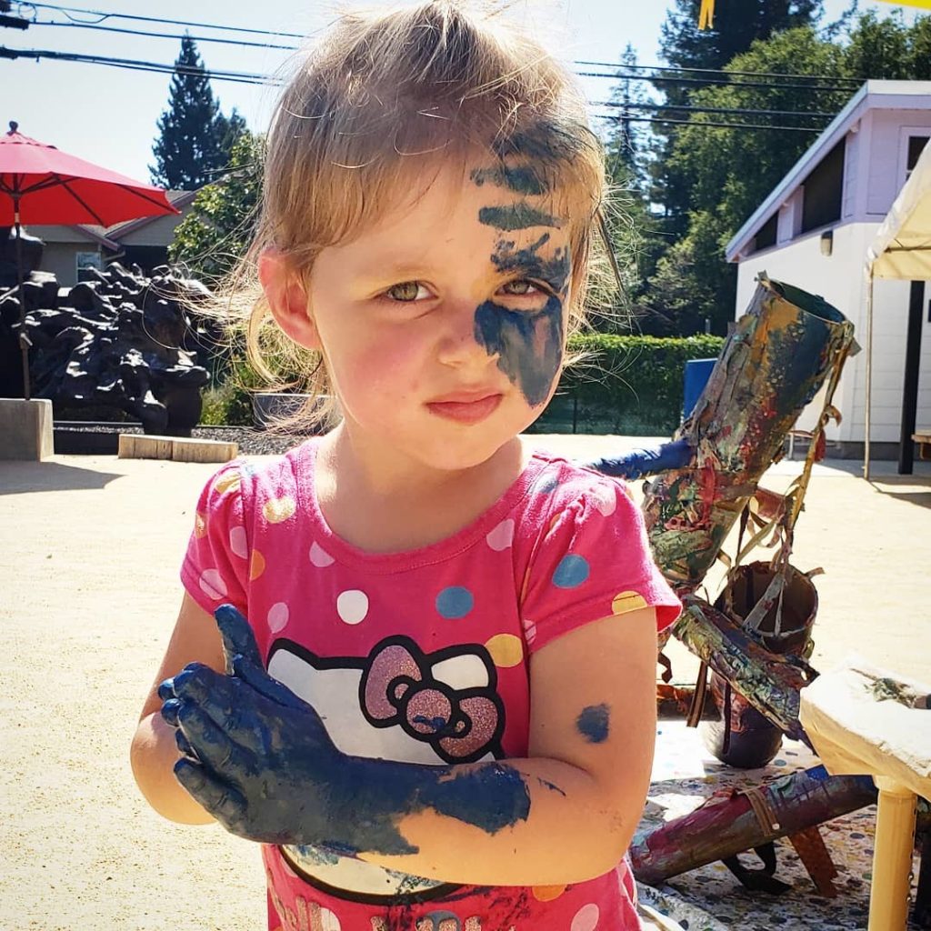 child with paint on face and hands