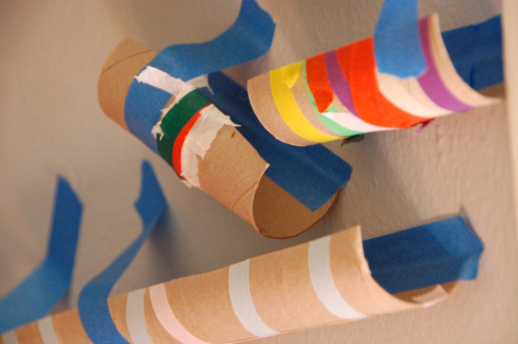 A marble run course handmade by children out of empty paper towel rolls and painters tape