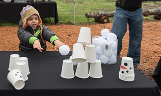 child knocking over cups with thrown snowball