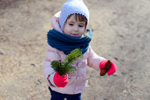 young child holding coniferous tree branch