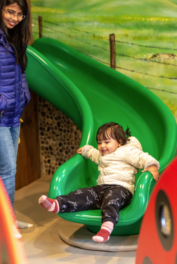 child sliding down slide at totopia