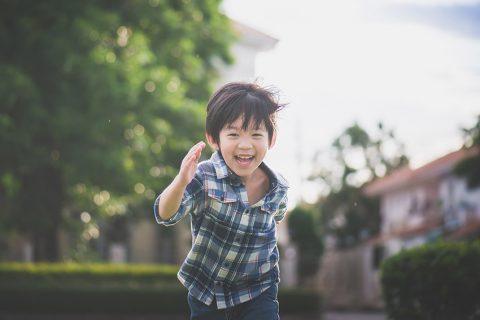 Little boy running around, laughing and playing outside