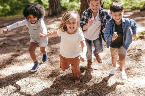 Kids running around playing in the forest