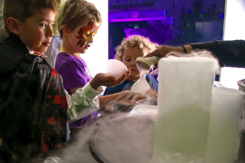 niños con disfraces de halloween haciendo el experimento científico de las burbujas de hielo seco
