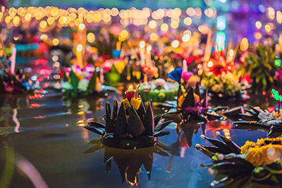 Fiesta de Loy Krathong con flores y farolillos de velas flotando sobre el agua para celebrar la fiesta de Loy Krathong en Tailandia.