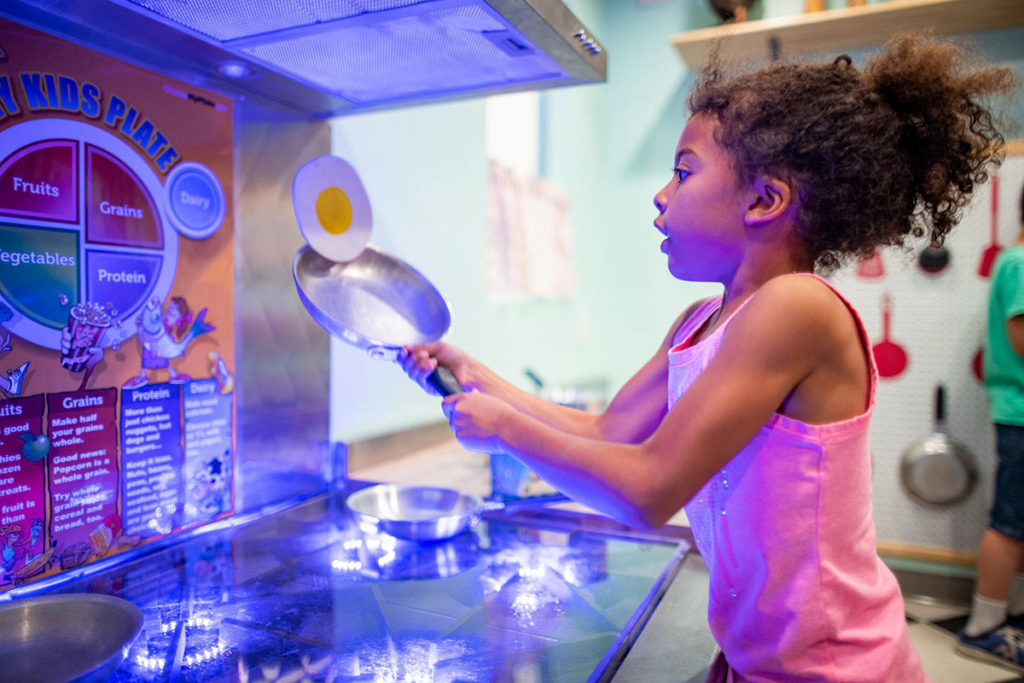una niña jugando en una cocina de mentira en el Museo de los Niños del Condado de Sonoma en Santa Rosa, Ca