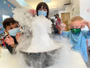 Tres niños participan en un experimento con hielo seco en el museo infantil del condado de sonoma