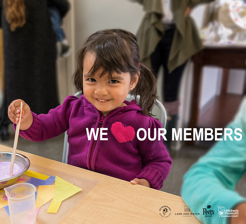 Niña sonriendo y pintando en el Museo de los Niños del Condado de Sonoma con un texto superpuesto que dice "Amamos a nuestros miembros"