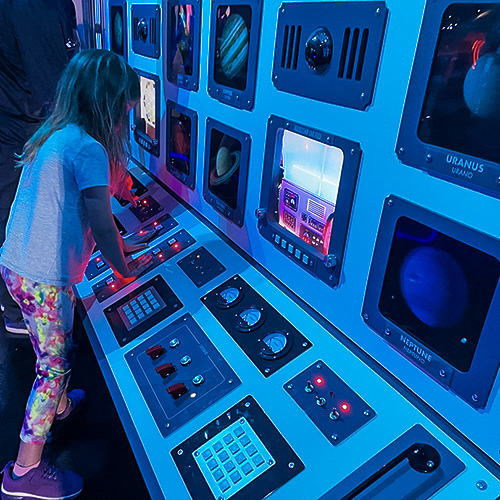 A child playing at a replica Mission Control Station in the Space Odyssey exhibit at the Children's Museum of Sonoma County