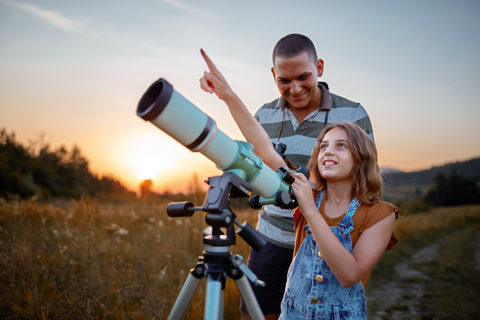 Father and daughter observing the sky with a telescope.