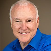 Professional headshot of local radio host Ted Williams wearing a blue polo shirt, with brown background