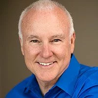 Professional headshot of local radio host Ted Williams wearing a blue polo shirt, with brown background