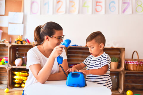 Adult and toddler playing with a blue toy/fake phone