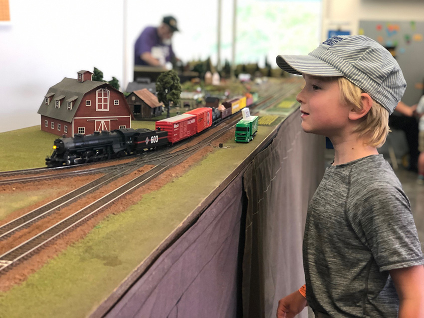 Un niño con gorra de revisor admirando una maqueta de tren en el evento Great Train Days del Museo de los Niños del Condado de Sonoma