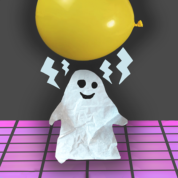 A kleenex tissue cut into a ghost shape with a balloon being used to make it dance via static electricity during a Halloween Activity for children called The Dancing Ghost Experiment