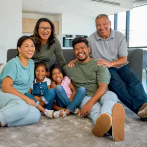 three generation family sits together including grandmother and grandfather, mother and father, and 2 young children